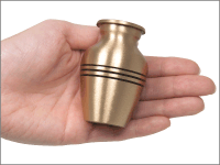 traditional brass small keepsake urn shown in hand for size comparison