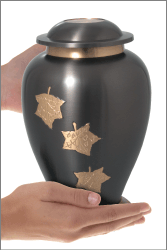 Midnight falling leaves brass cremation urn shown in hand for size reference