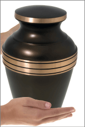 cremation urn dark bronze gold band brass shown in hands for size scale