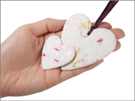 small and large plantable hearts shown in hand for size scale